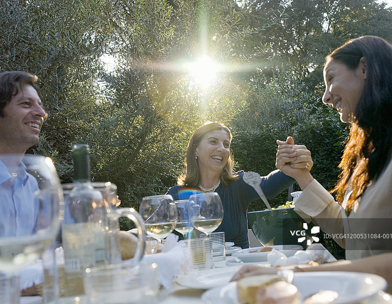 中年母亲在花园里的家庭聚餐中牵着女儿的手图片素材