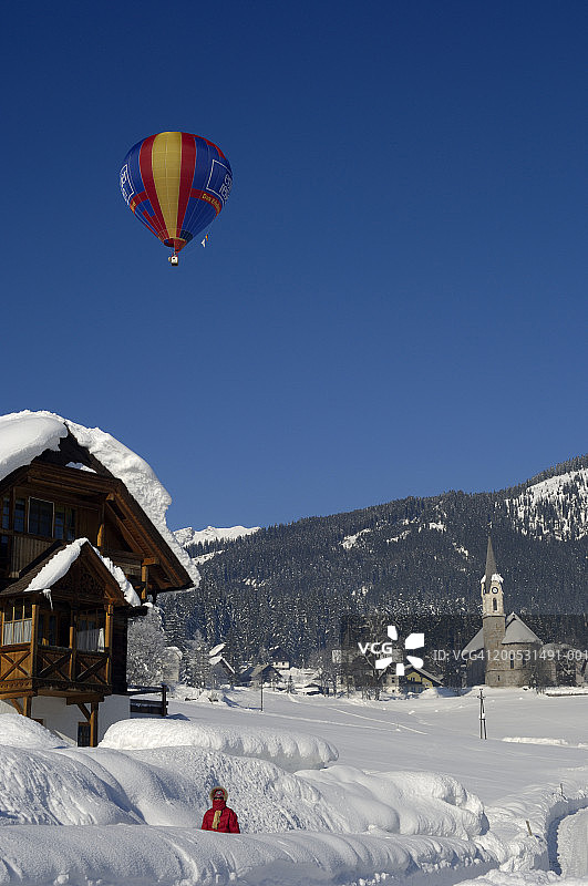 奥地利戈绍：雪中村庄上空的热气球图片素材