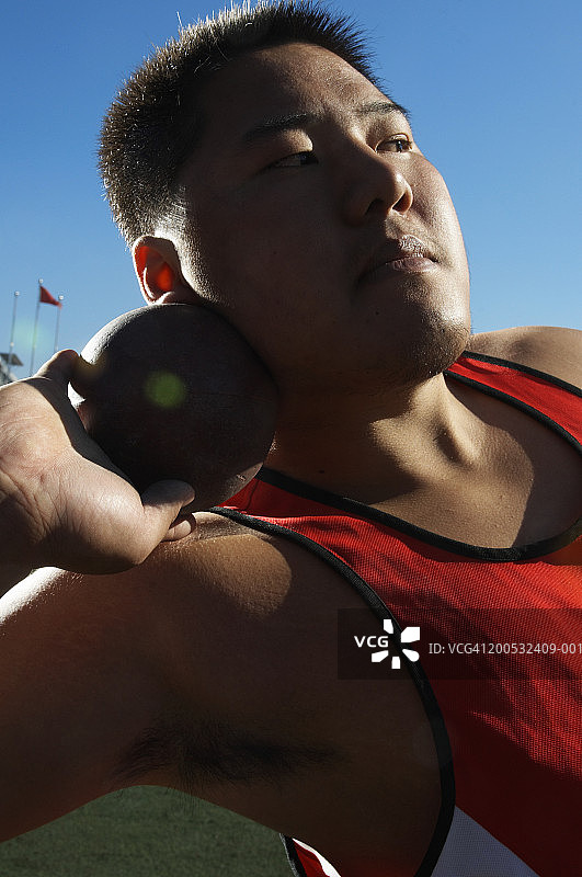 青年准备掷铅球，看向别处图片素材