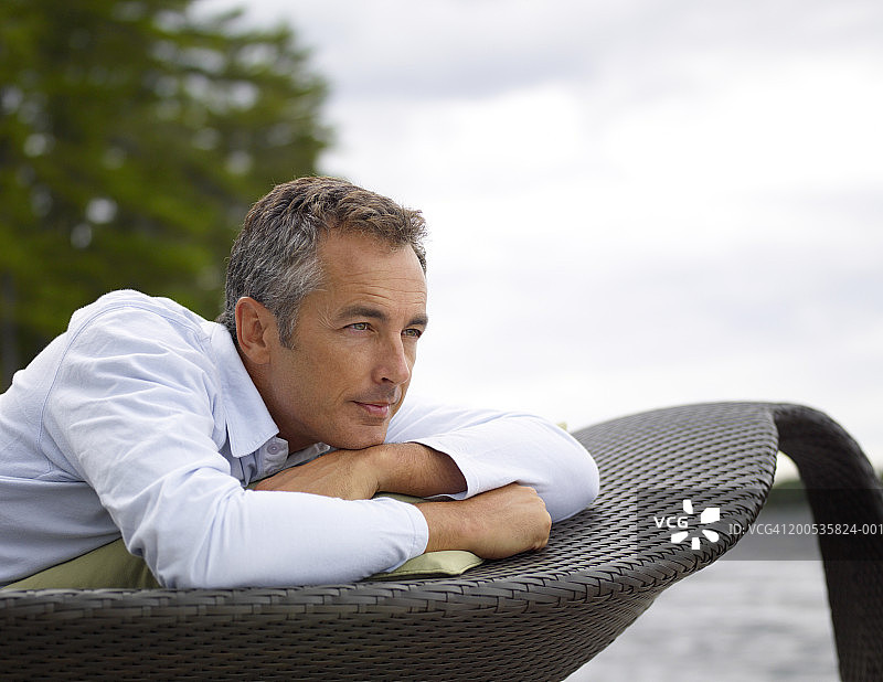 中年男人躺在湖边沙滩椅上图片素材