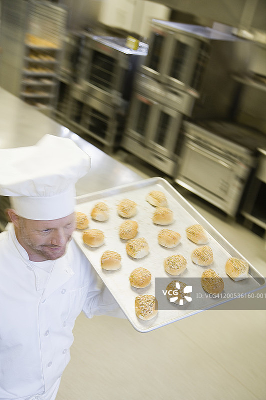 中年男性面包师端着一盘烘焙食品（动态模糊）图片素材