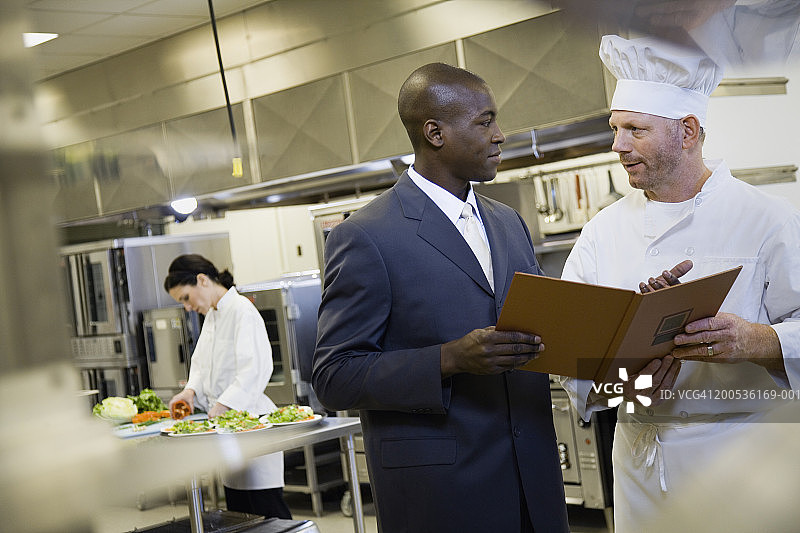 男餐厅经理与厨师在厨房讨论菜单图片素材