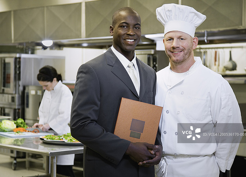 厨房里厨师旁的男餐厅经理肖像图片素材