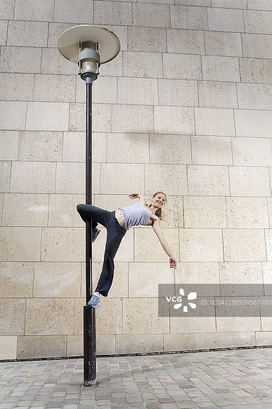 年轻女人悬挂在灯柱上图片素材