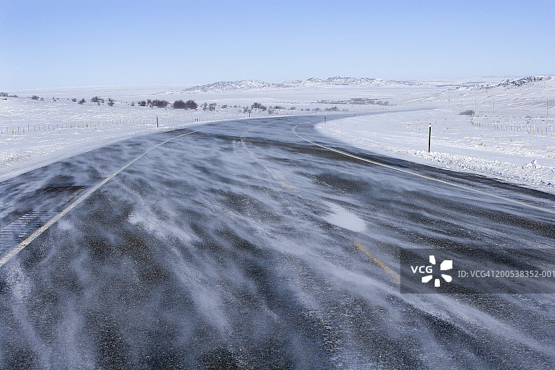 美国怀俄明州恩坎普门特，风吹着雪穿过冰冻的高速公路图片素材
