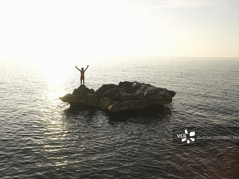 意大利撒丁岛卡拉戈诺内男子站在岛上举起双臂图片素材