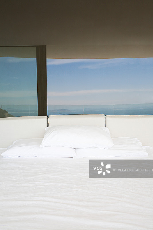 倒映着海洋和天空的玻璃床头白色床铺（竖版）图片素材