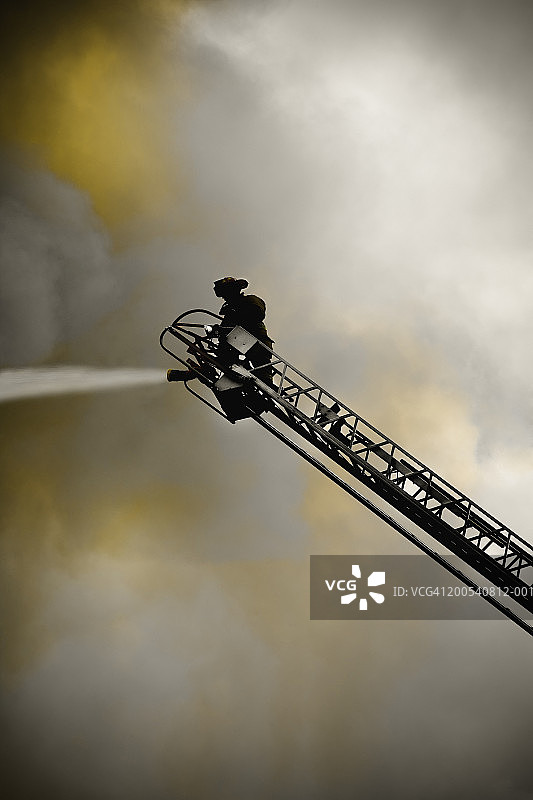 消防员在梯子上灭火，低角度视图图片素材