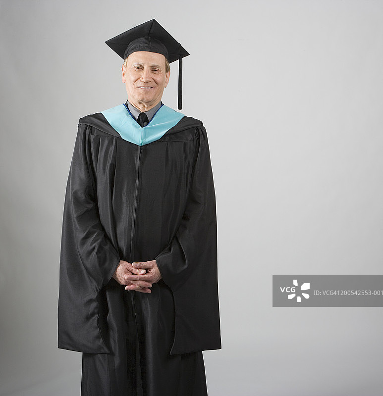 穿着学位礼服，双手交叉微笑的老年男人肖像图片素材