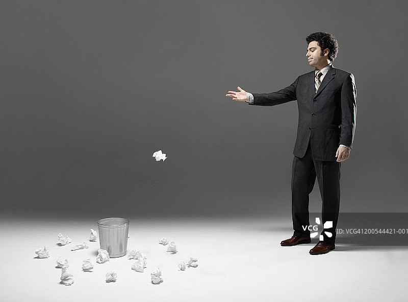 商务人士将废纸扔进垃圾桶，工作室拍摄图片素材