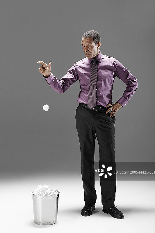 将废纸扔进垃圾桶的商人（影棚拍摄）图片素材