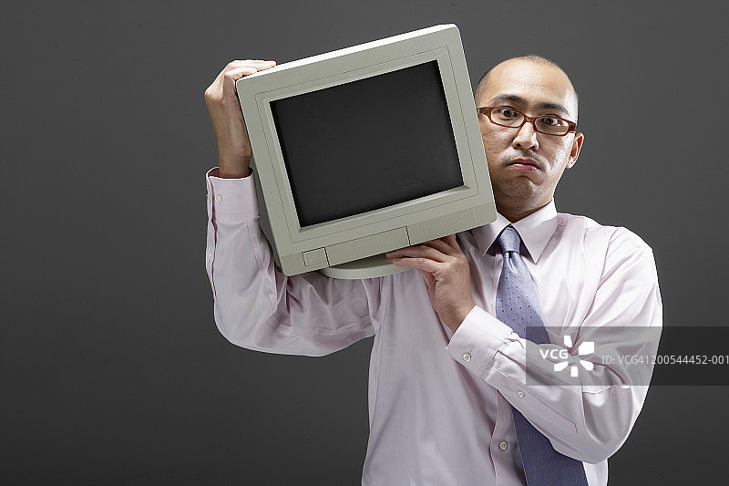 搬运沉重电脑显示器的商人肖像图片素材