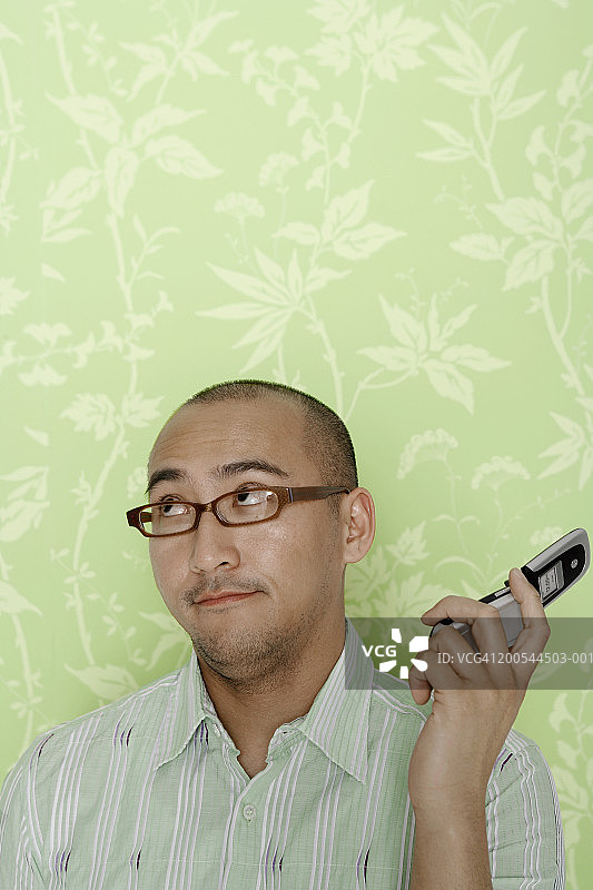 在室内，男人拿着远离耳朵的手机图片素材