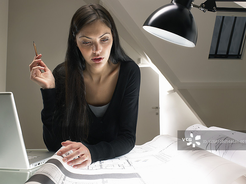 年轻女人在桌旁查看建筑图纸图片素材
