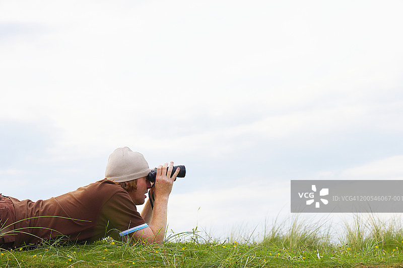 爱尔兰多尼戈尔郡巴利马斯托克海湾使用双筒望远镜的男人图片素材