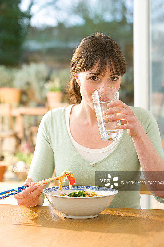 年轻女人吃面条喝水肖像图片素材