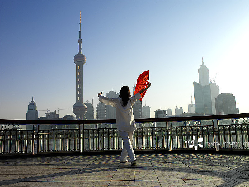 中国女人在浦东天际线前跳扇子舞图片素材