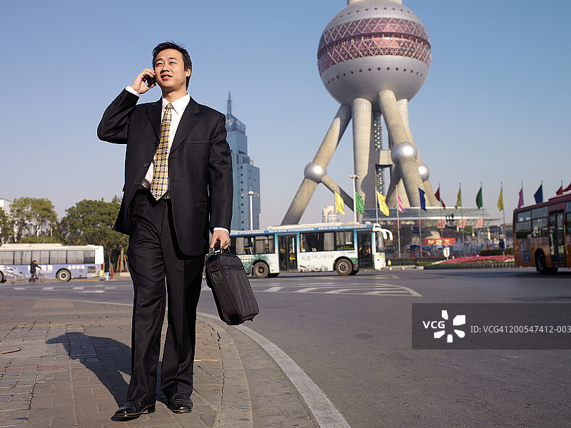 在东方明珠电视塔前使用手机的中国商人图片素材