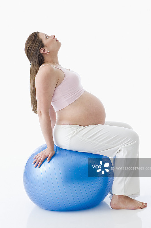 孕妇坐在健身球上，侧视图图片素材