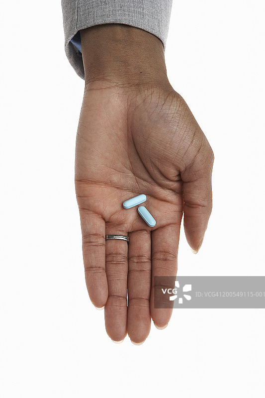 手持两颗药丸的年轻女人手部特写图片素材