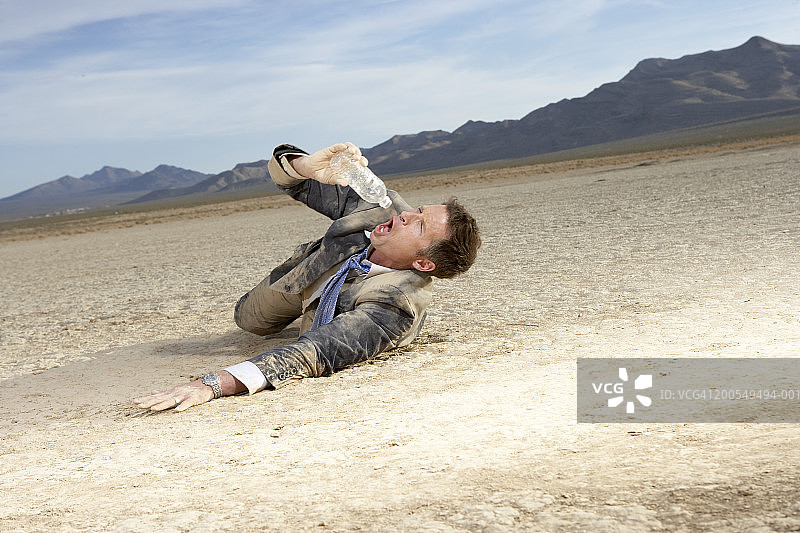 在干涸的湖床上挣扎并饮水的商人图片素材