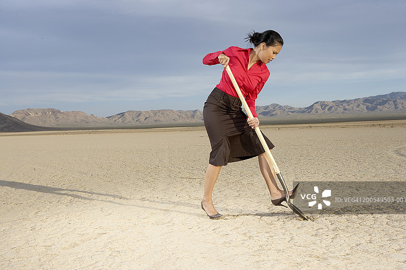 女商人在干涸的湖床上挖掘图片素材