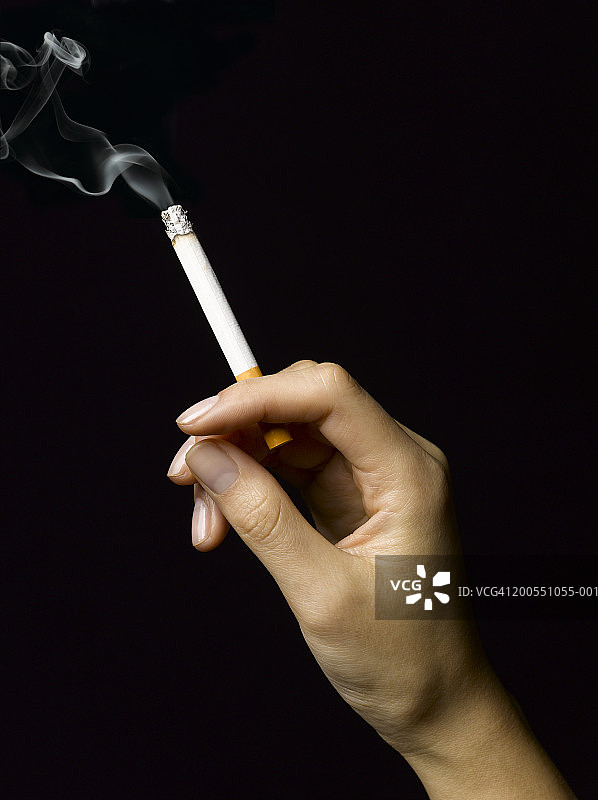 手拿燃烧香烟的年轻女人图片素材