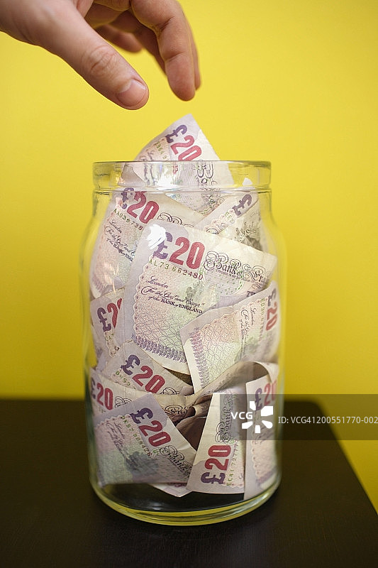 手从玻璃罐中拿二十英镑纸币特写图片素材