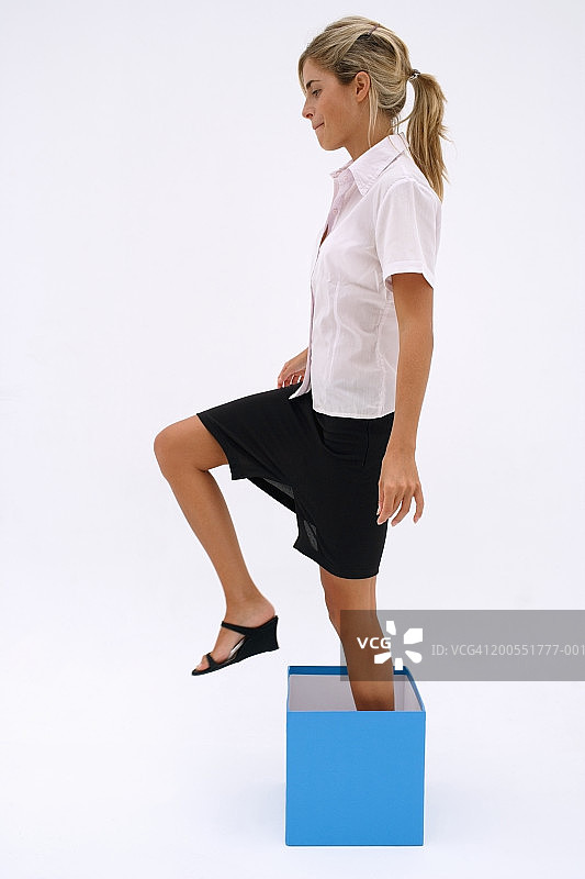 年轻女商人走出蓝色盒子，侧视图图片素材