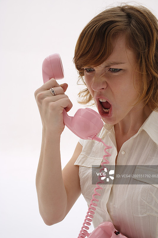 年轻女人拿着粉色电话听筒喊叫，特写图片素材