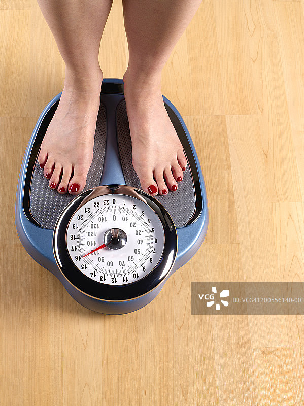 站在木地板上的体重秤上的女人（局部）图片素材