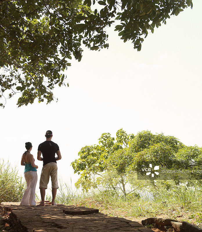 年轻情侣站在乡下，后视图图片素材
