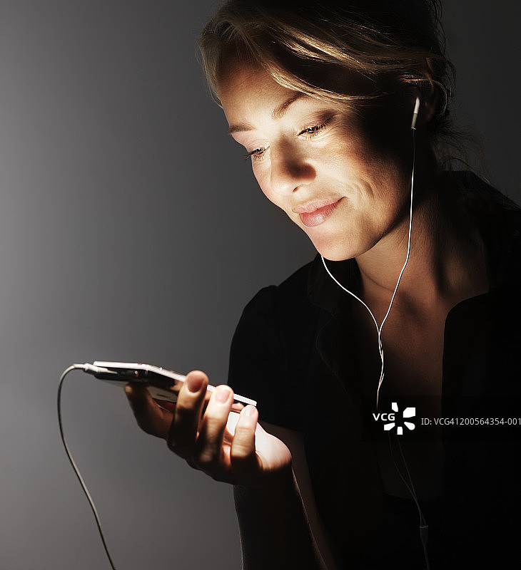 年轻女人听着MP3播放器，微笑特写图片素材