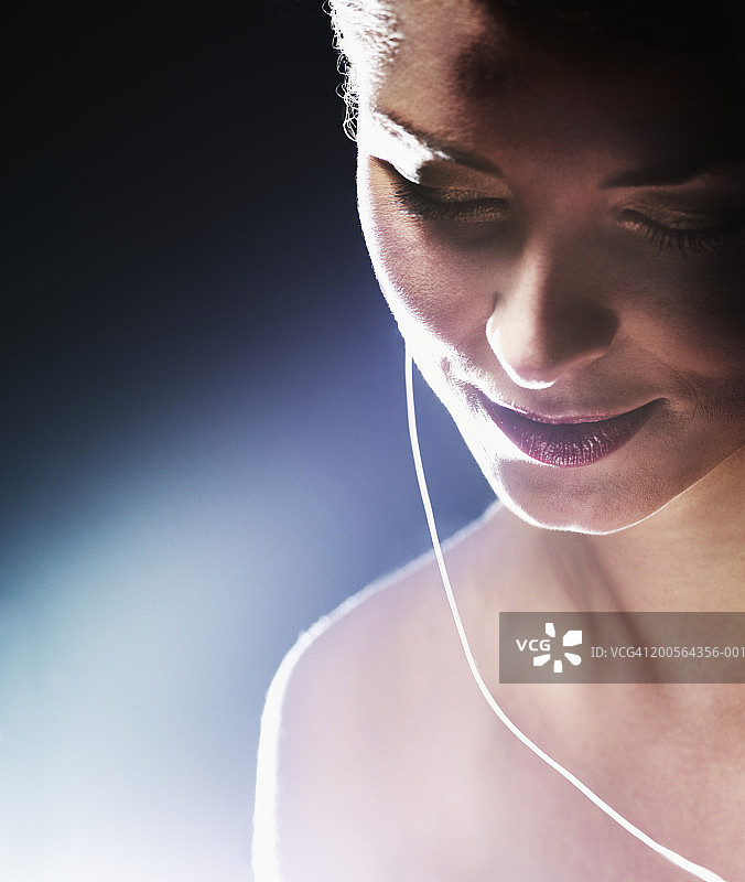 年轻女人听着MP3播放器，微笑特写图片素材