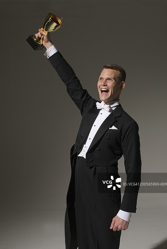 穿燕尾服手持奖杯大喊的男人图片素材