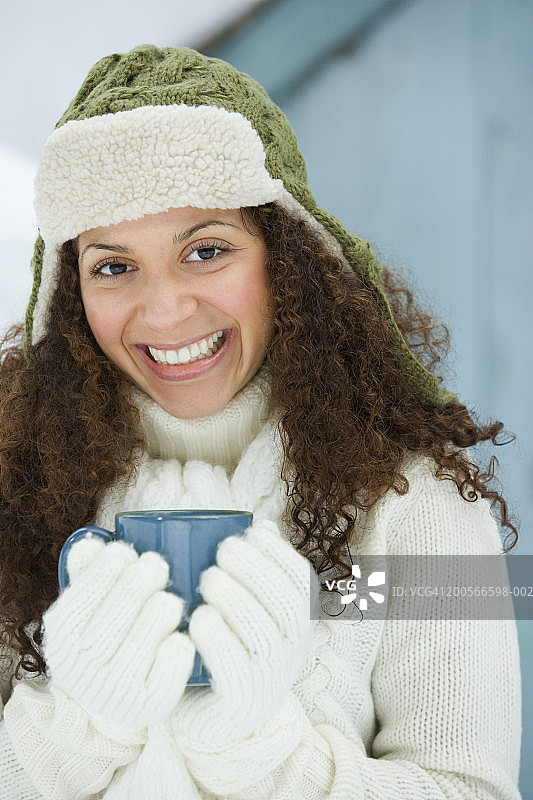 戴帽子手拿杯子的微笑年轻女子肖像图片素材