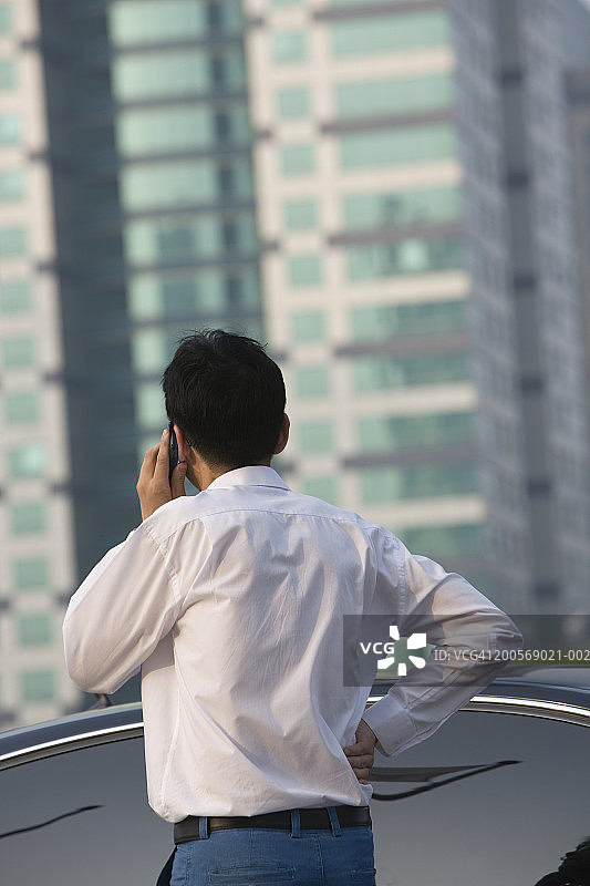 站在车旁用手机交谈的中年男人（后视图）图片素材