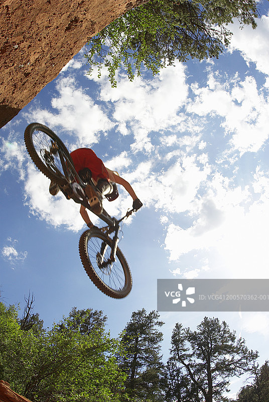 骑山地自行车的男人表演跳跃，低角度拍摄图片素材