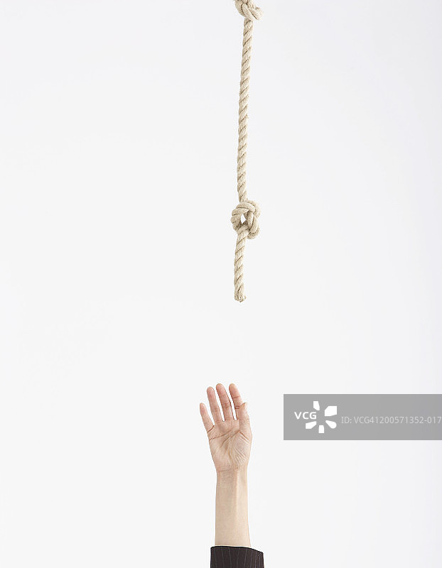 伸手去抓上方悬挂的绳子的人,手部特写图片素材