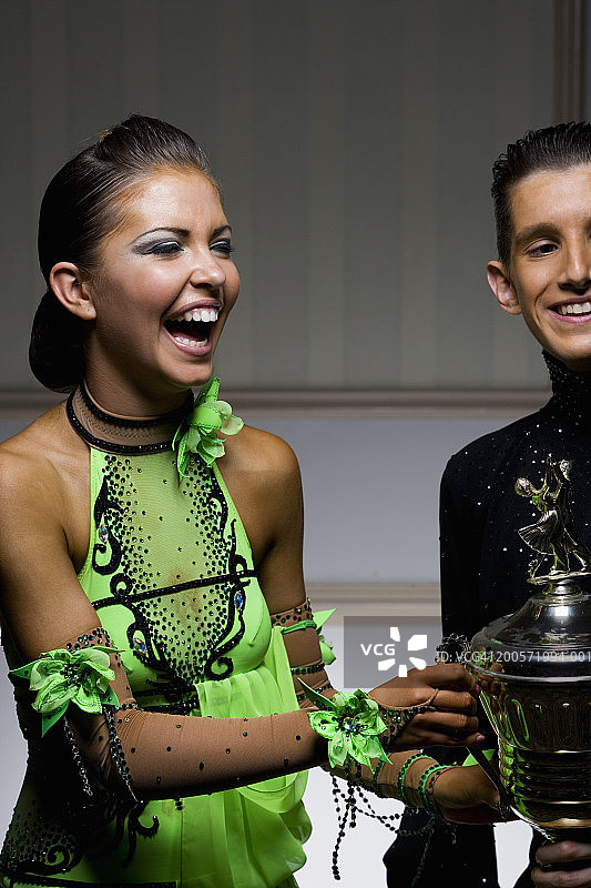 手捧奖杯开怀大笑的青少年情侣图片素材