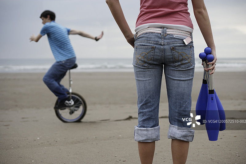 骑独轮车的年轻男人，前景是女人图片素材