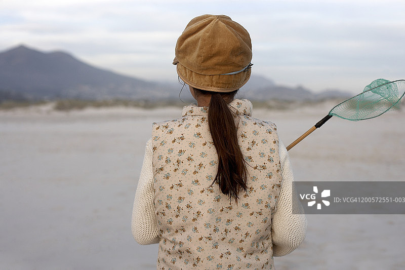 在海滩上拿着网行走的女孩（8-10岁）背影图片素材