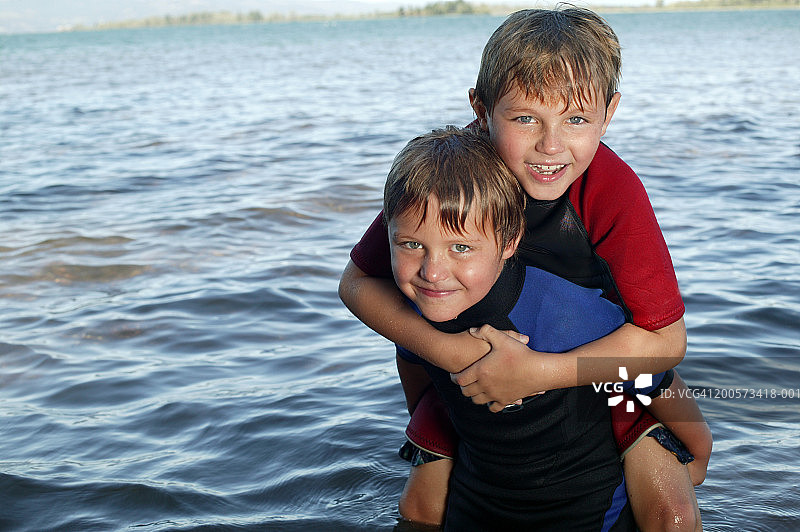 男孩（6-7岁）背着朋友，面带微笑的肖像照图片素材