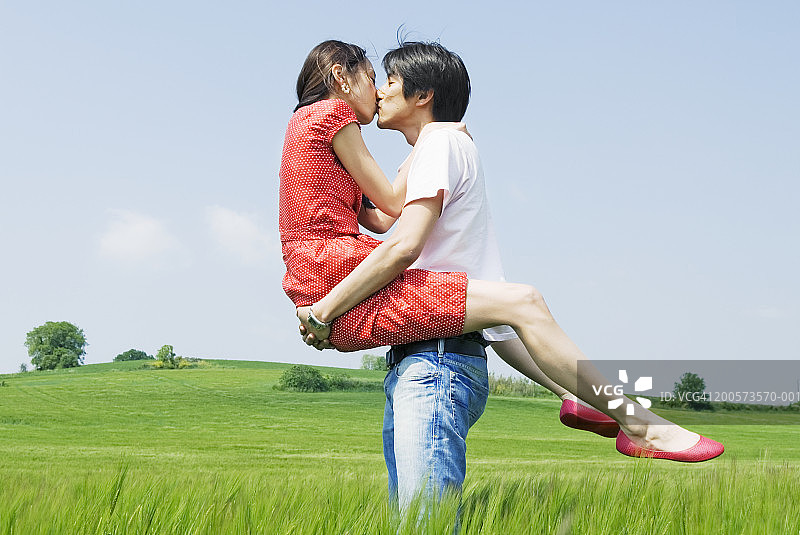 法国盖亚克，男子抱起站在长草地里的女子图片素材