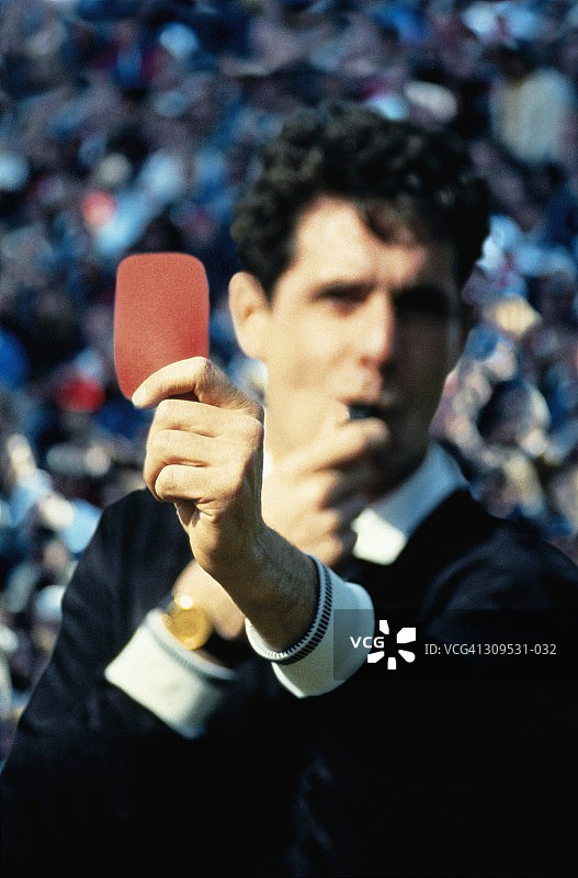 足球裁判出示红牌，背景是人群，特写镜头图片素材