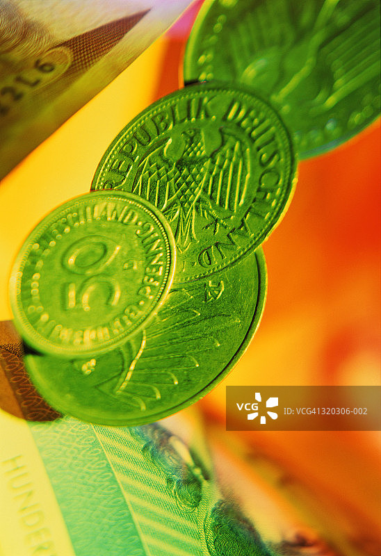 绿色背景上的德国货币、芬尼硬币和马克纸币图片素材