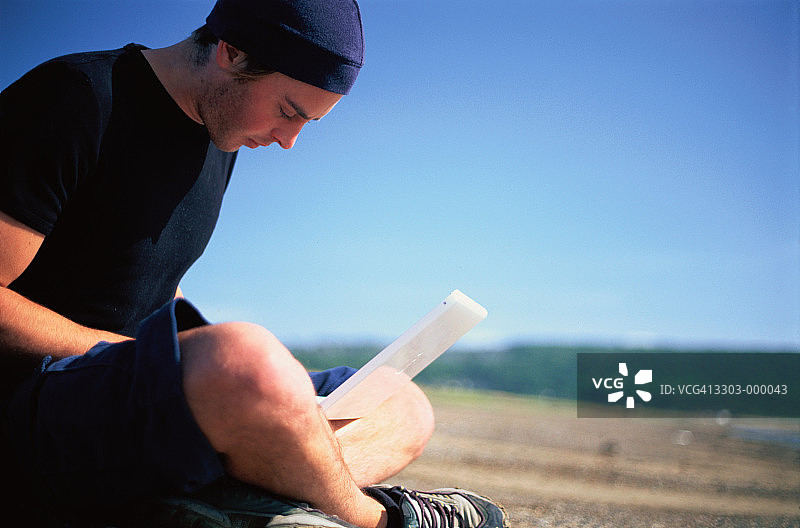 在海滩上使用笔记本电脑的男人图片素材