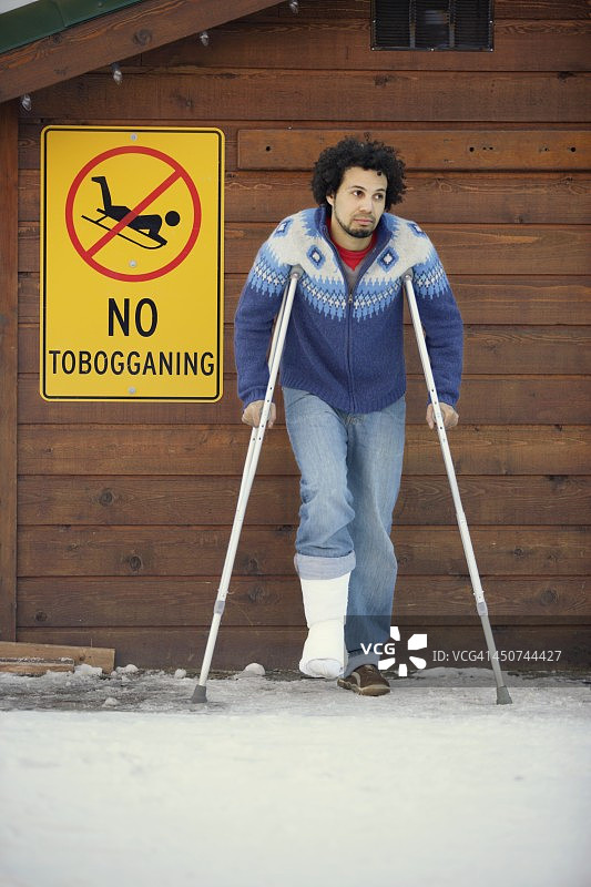 在“禁止滑雪”标志附近拄着拐杖的男人图片素材
