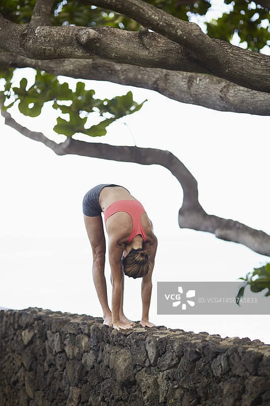 在石墙上锻炼的年轻女人图片素材