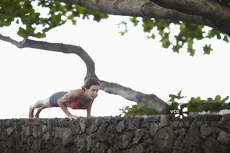 在石墙上锻炼的年轻女人图片素材